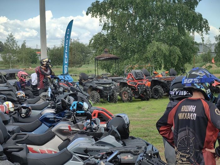 Ряд квадроциклов и багги на площадке сбора у флагов CFMOTO