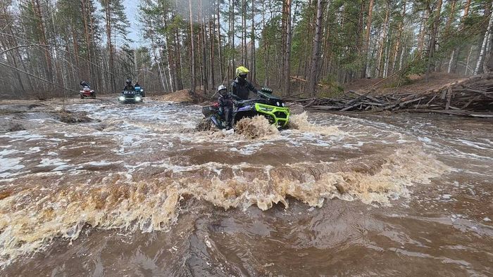 Квадроцикл форсирует залитую весенней водой лесную дорогу