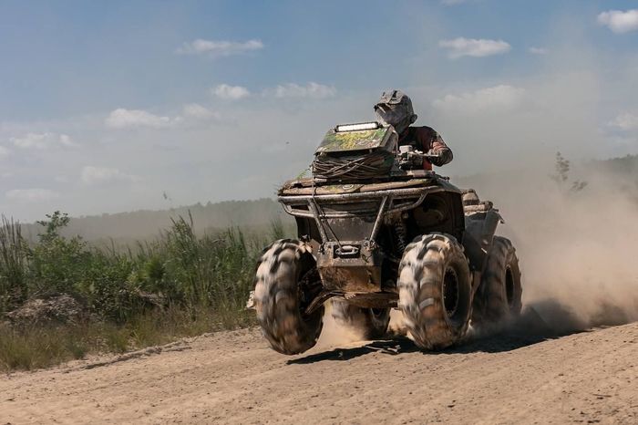 Квадроцикл вылетает из облака пыли на трассе